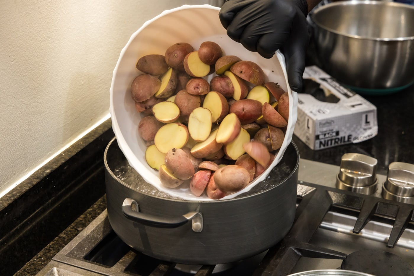 adding sliced baby red potatoes to pot of water