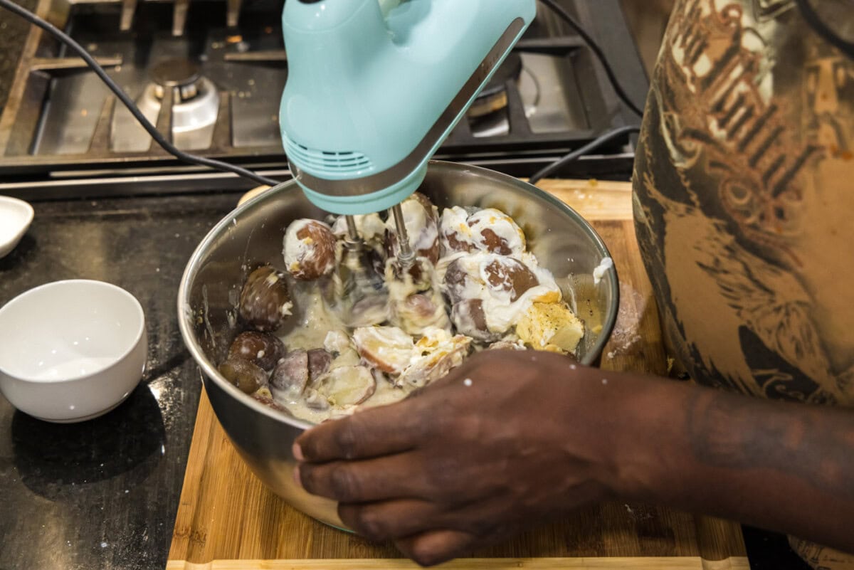 blending mashed potatoes in a bowl with a mixer