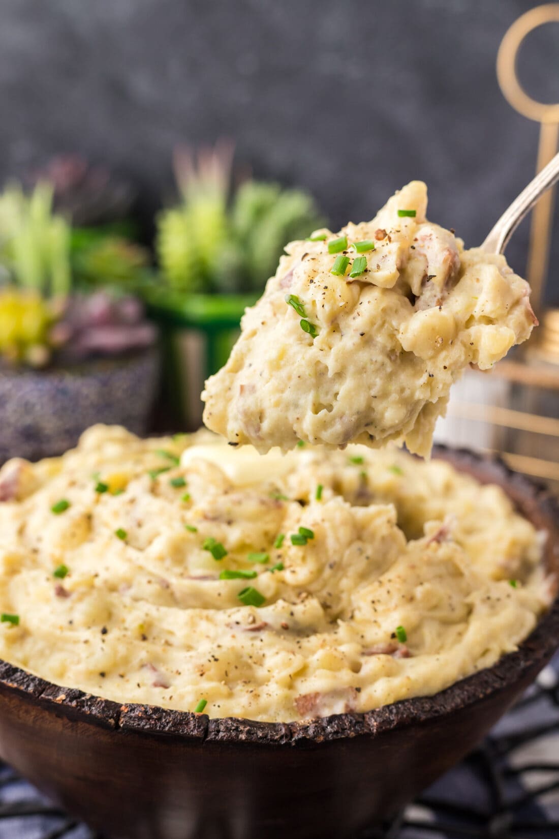 Spoonful of Garlic Mashed Potatoes being lifted above a bowl of Garlic Mashed Potatoes