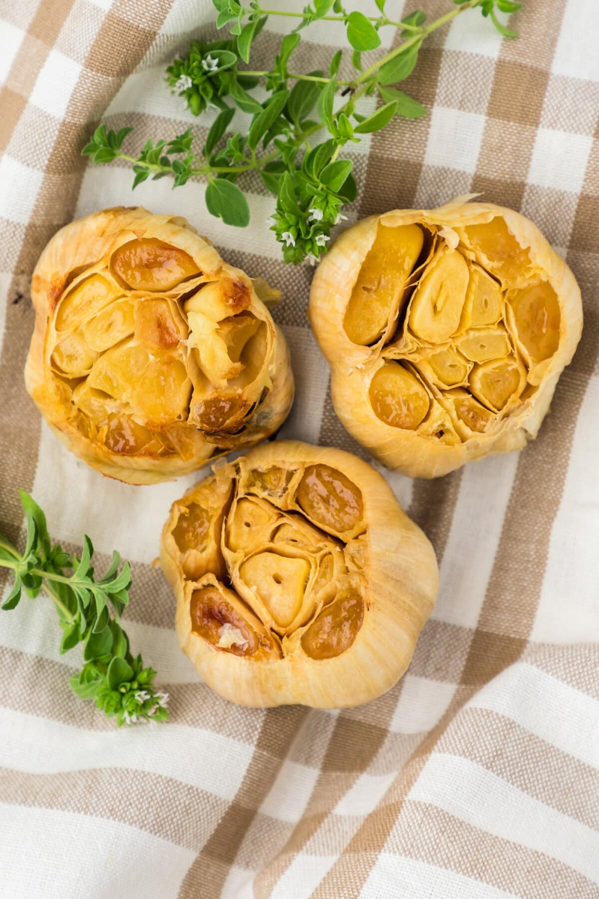 Close up photo of three bulbs of roasted garlic on a towel