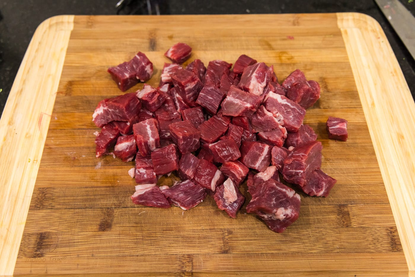 flank steak cubed on a cutting board