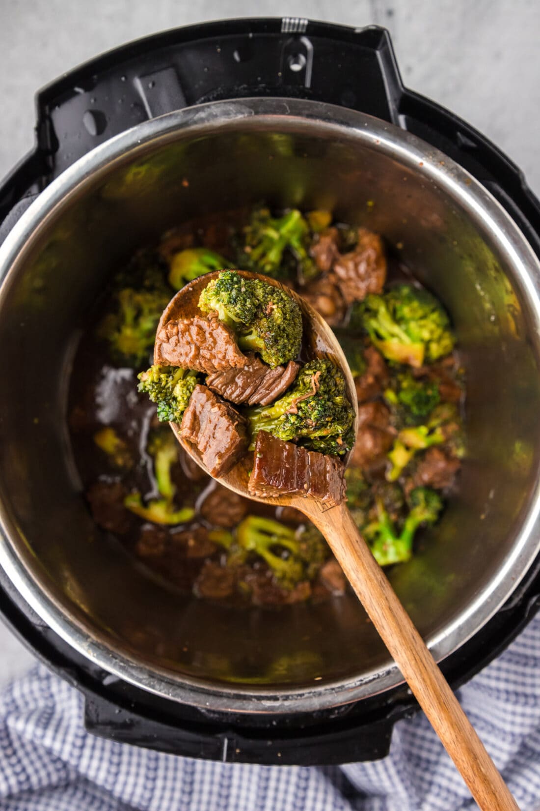 Spoon of Instant Pot Beef and Broccoli held above an instant pot