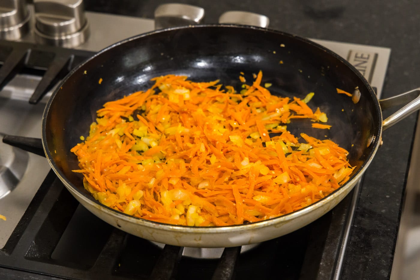 cooking garlic, onion, and shredded carrots in a skillet