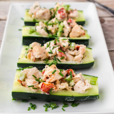 Four Lobster Cucumber Boats on a white serving platter topped with chives