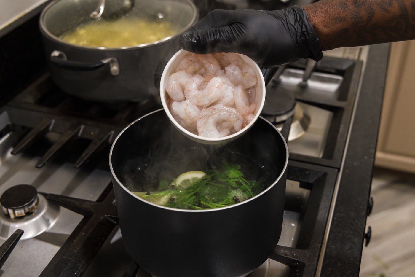 adding raw shrimp to hot water with cilantro