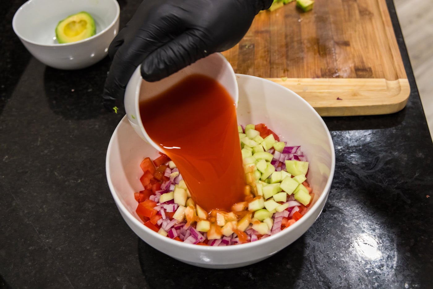 pouring clamato juice into vegetables mixture