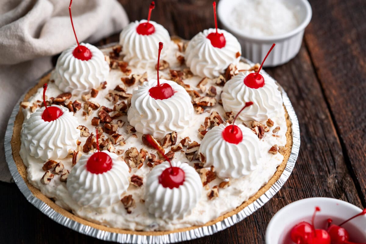piped cool whip and maraschino cherries on top of million dollar pie