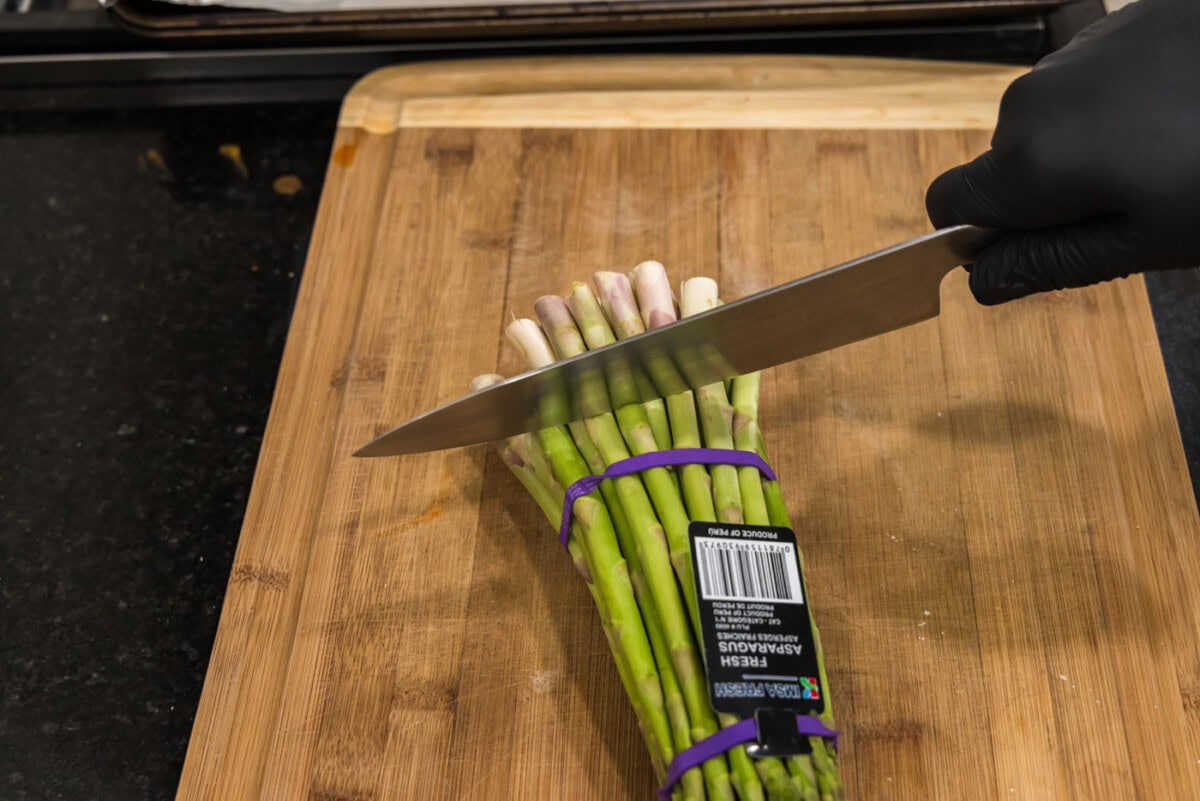 knife cutting woody end of asparagus spears