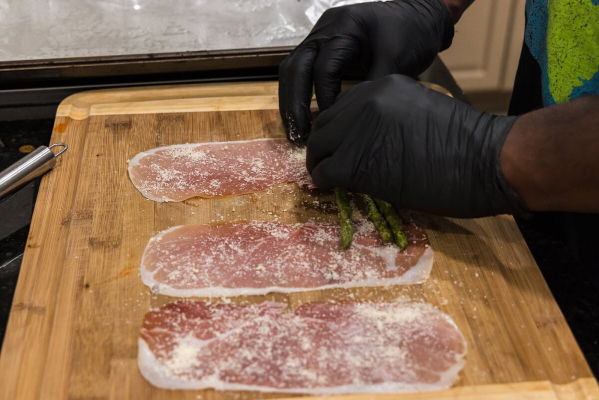 hands rolling asparagus spears in prosciutto