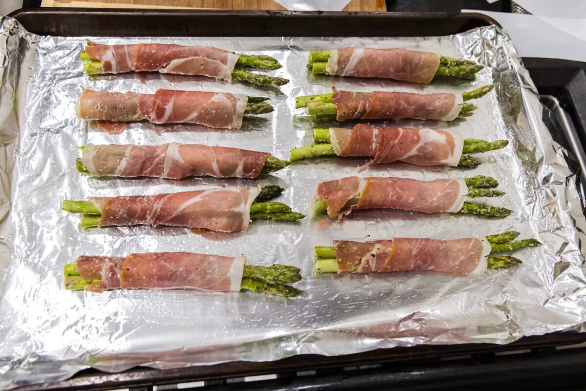 prosciutto wrapped asparagus on a baking sheet