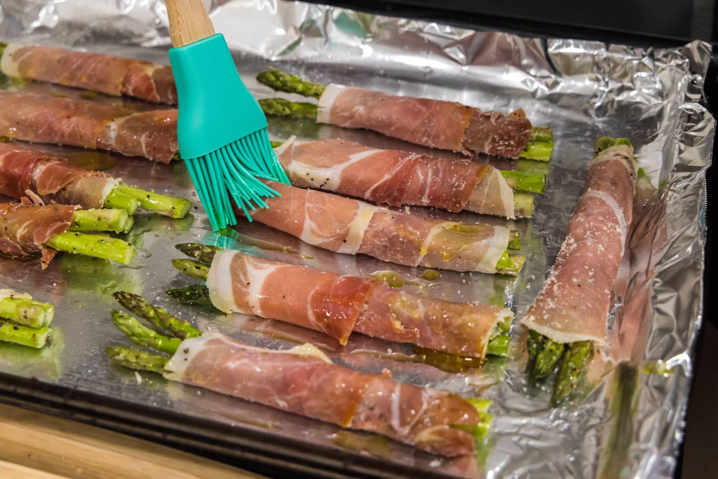 basting prosciutto asparagus with olive oil mixture