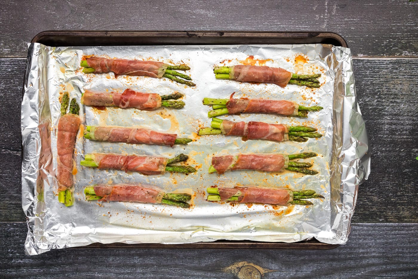 prosciutto wrapped asparagus on a baking sheet