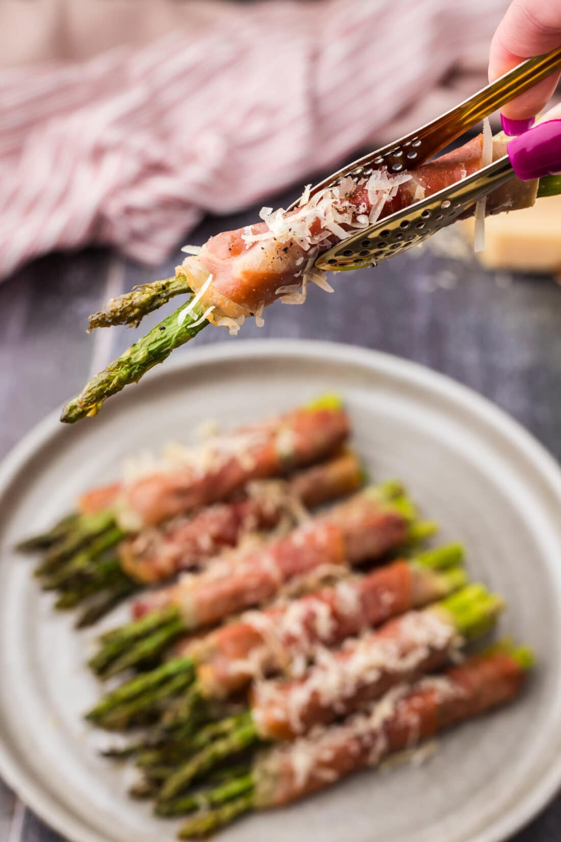 Tongs holding up Prosciutto Wrapped Asparagus