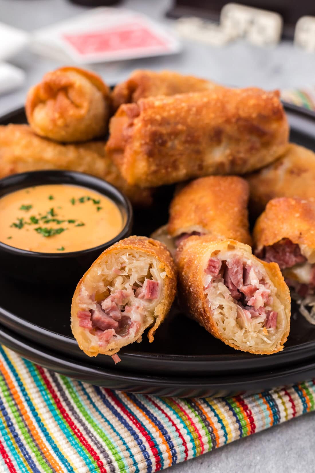 Close up photo of Reuben Egg Rolls on a plate with a bowl of thousand island dressing