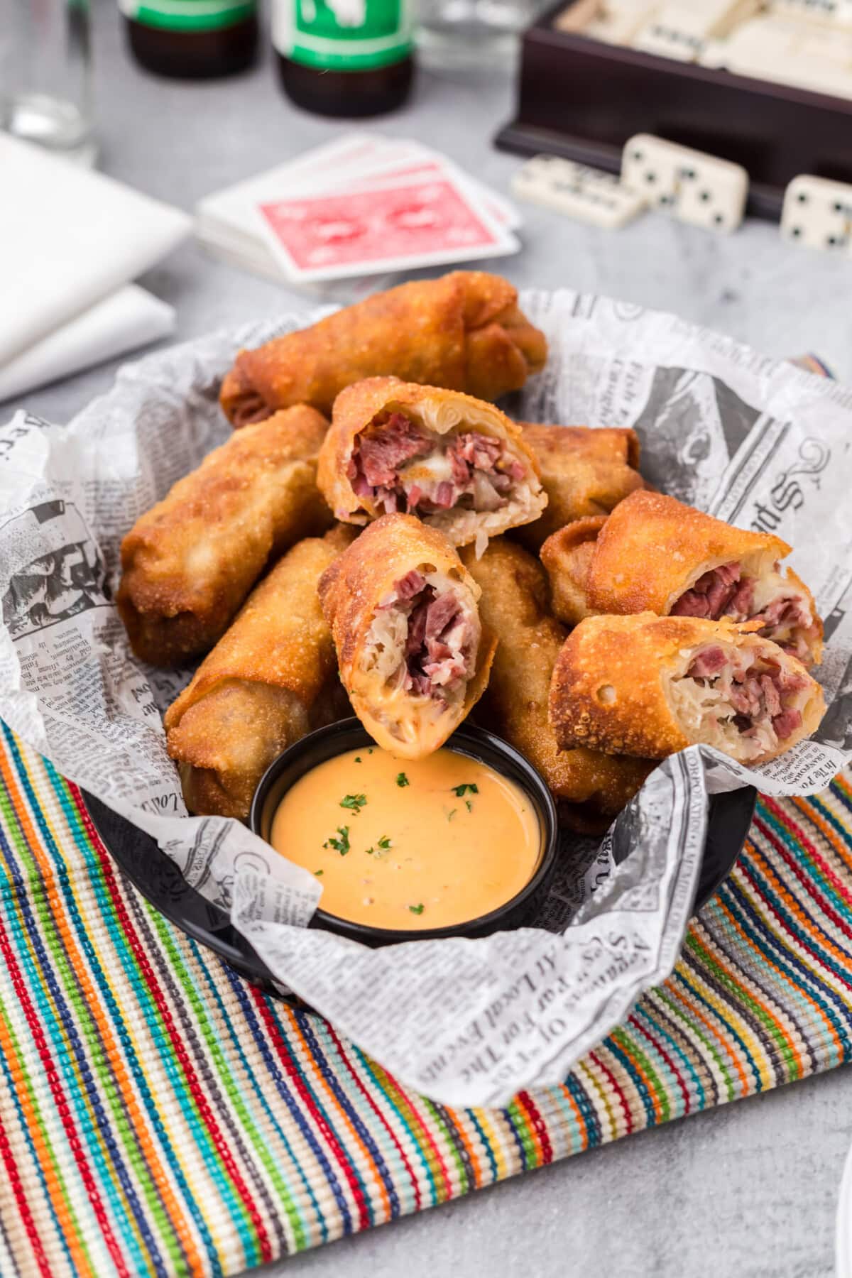 Reuben Egg Rolls cut in half resting in a basket with sauce