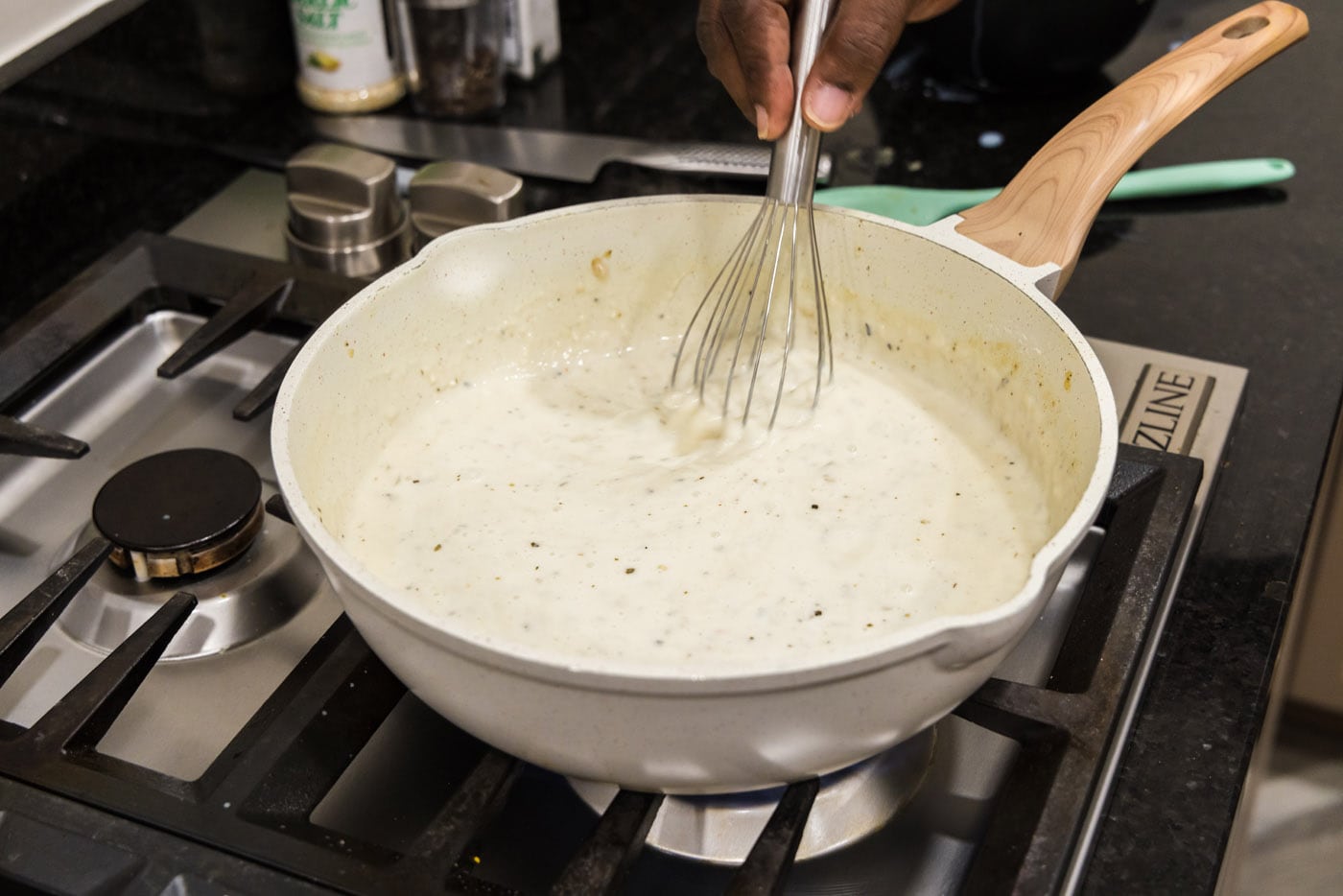 whisking cream sauce in a skillet