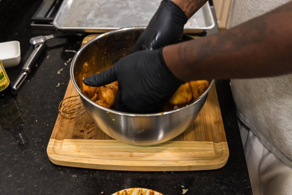 hands tossing potatoes in spice blend