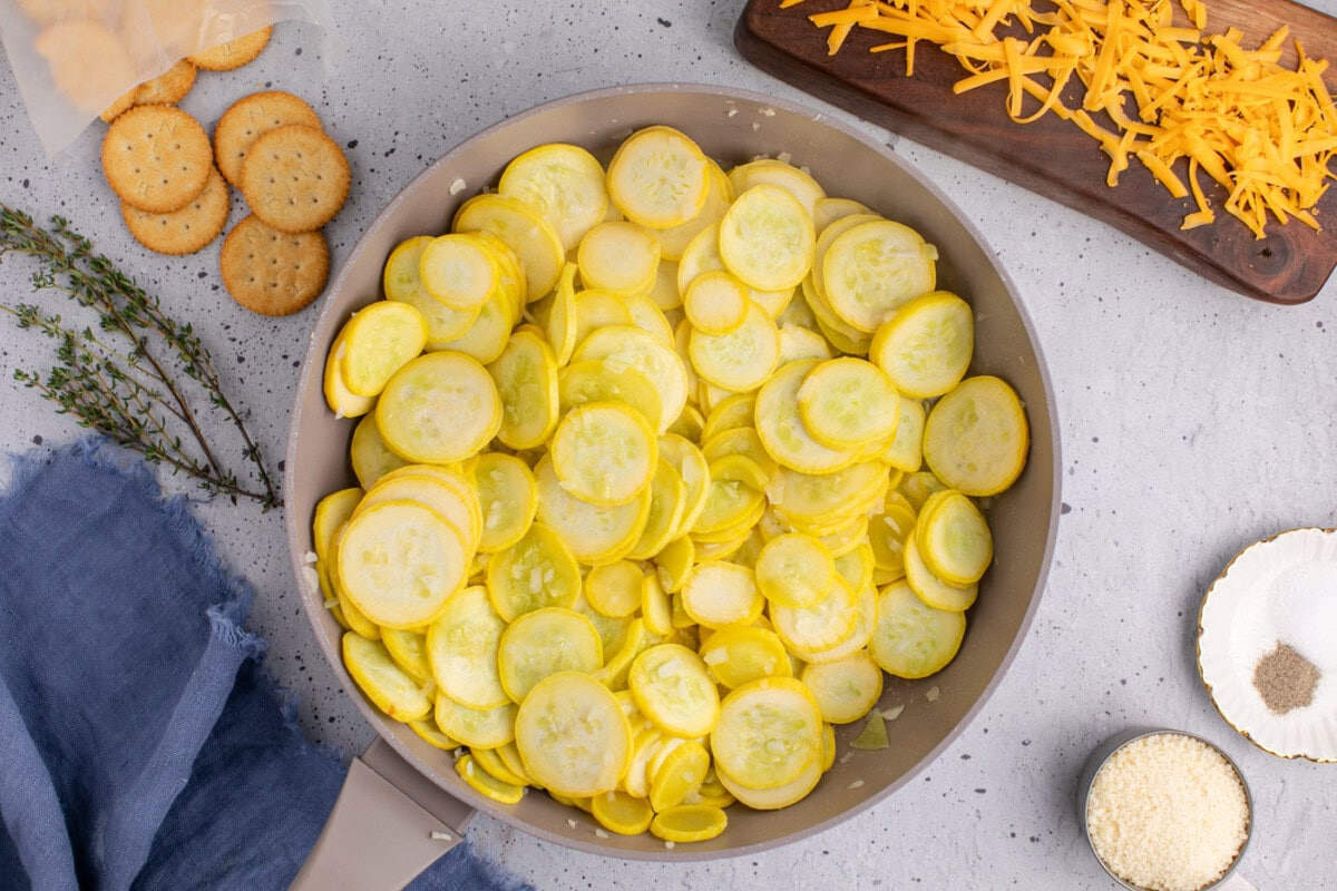 partially cooked squash slices and onion in a skillet