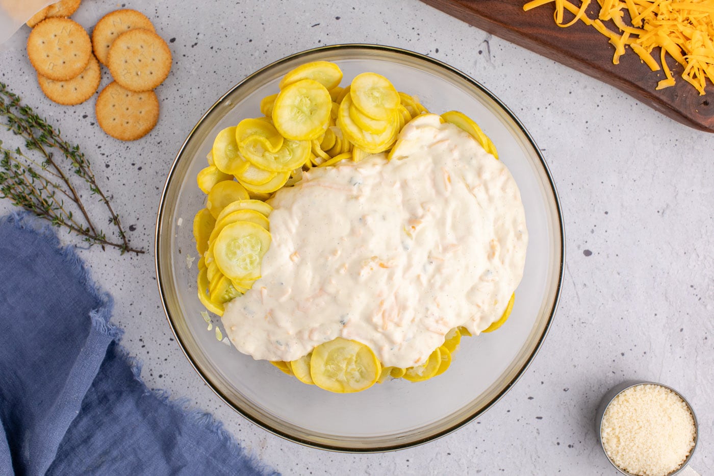 adding sour cream filling to sliced yellow squash in a mixing bowl