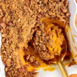 Spoonful of Sweet Potato Souffle resting in a baking dish of Sweet Potato Souffle