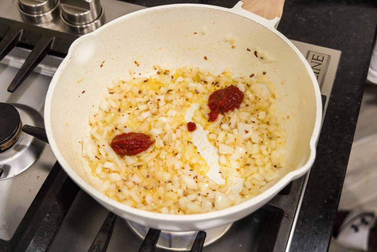 tomato pasta added to skillet of onion mixture