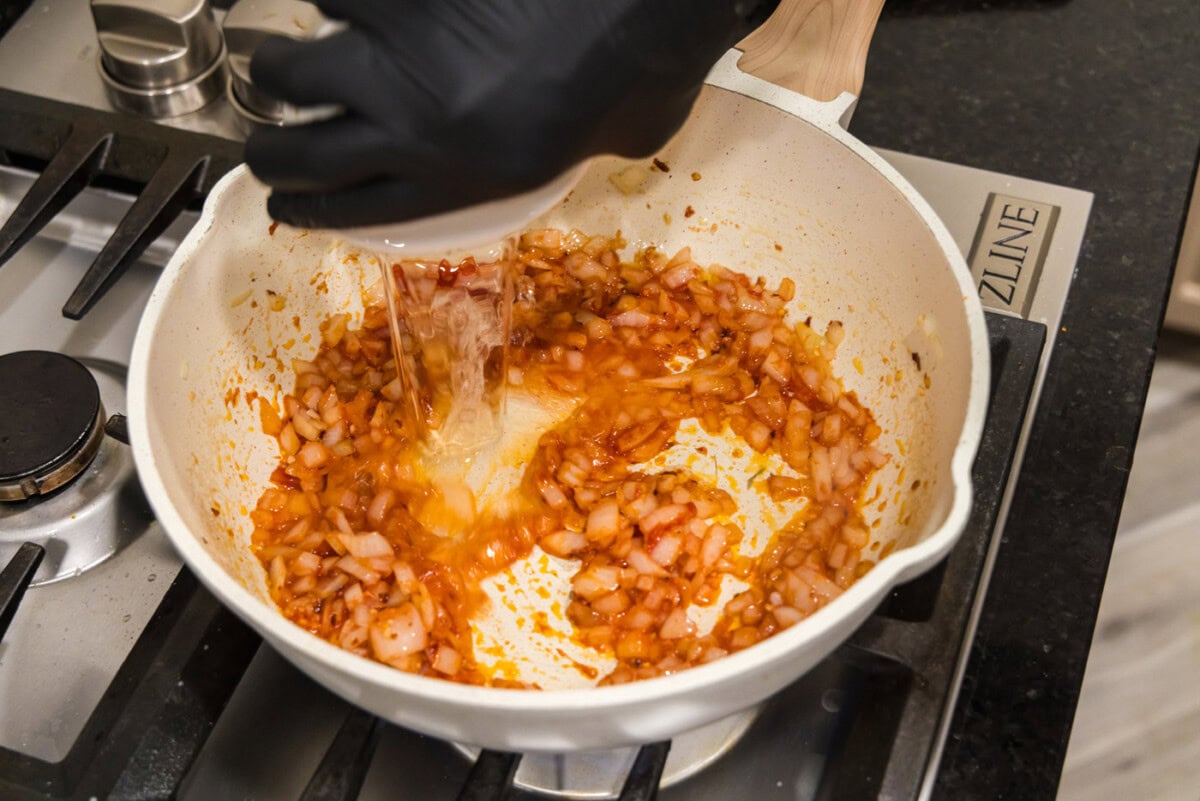 pouring vodka into tomato sauce
