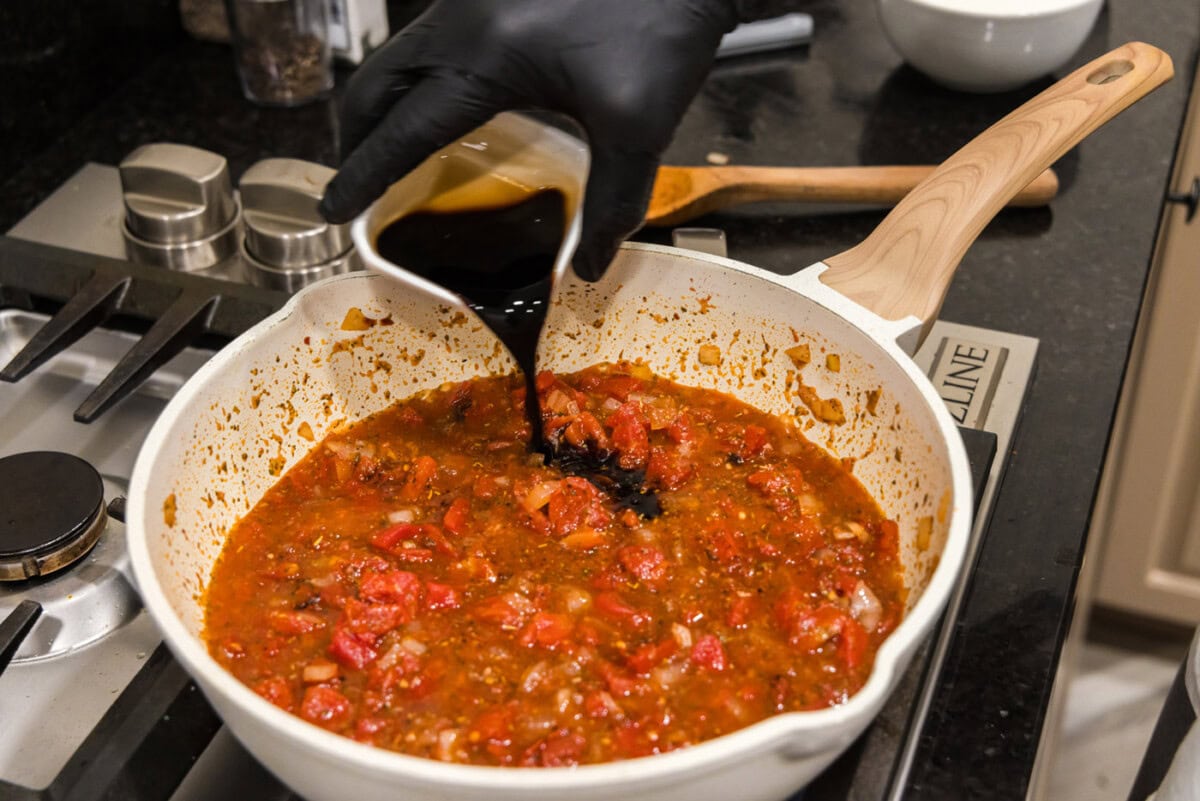 pouring balsamic vinegar into skillet with vodka sauce