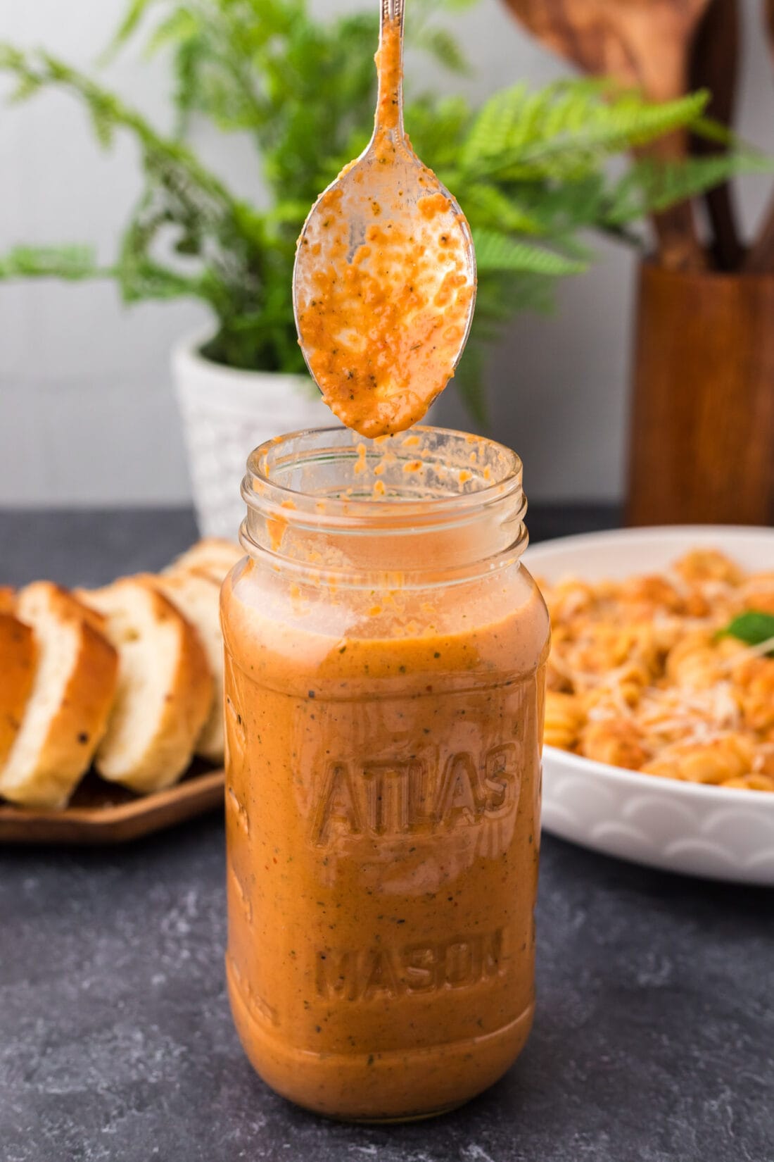 Spoon covered in Vodka Sauce being lifted out of a jar of Vodka Sauce
