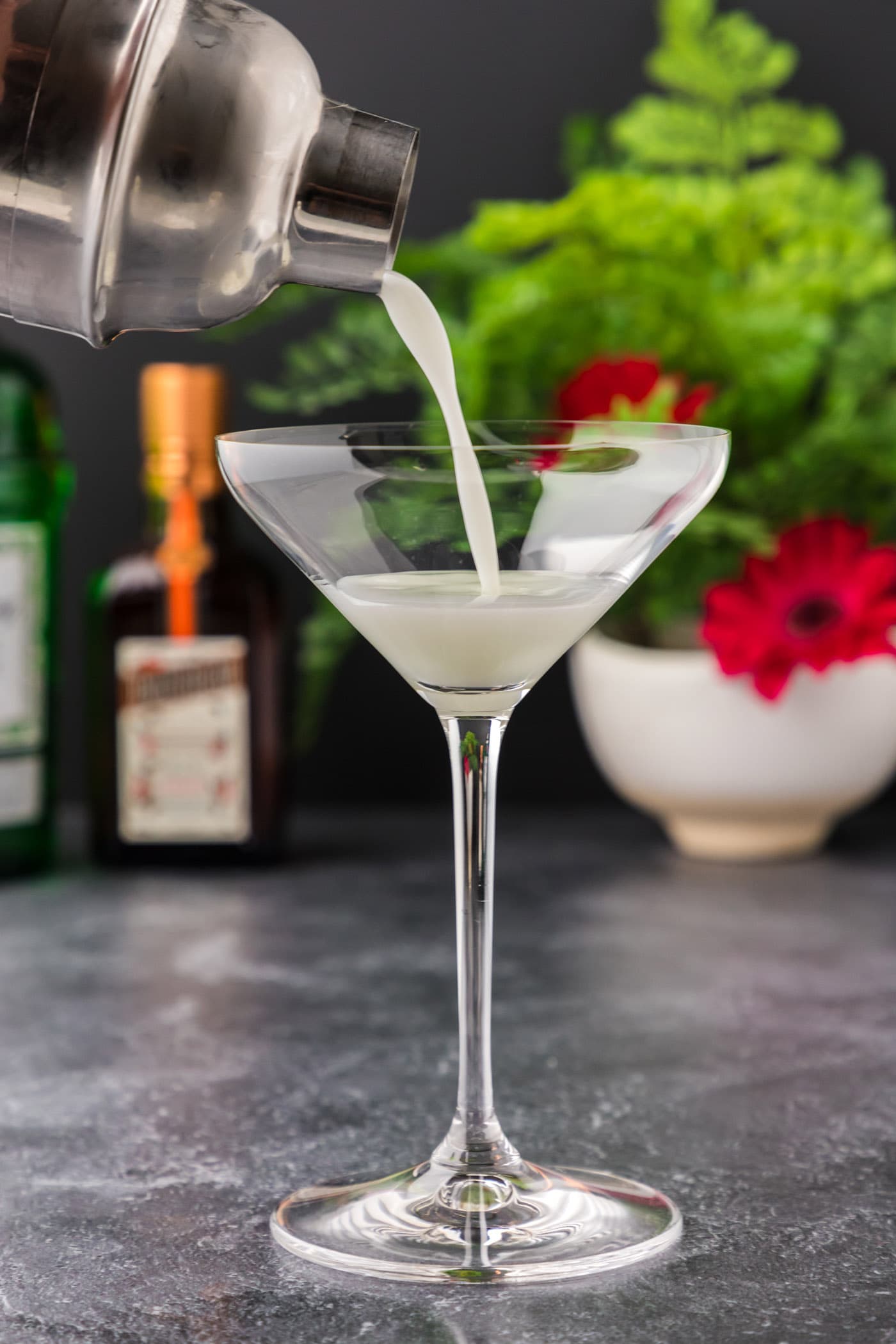 straining white lady cocktail into martini glass