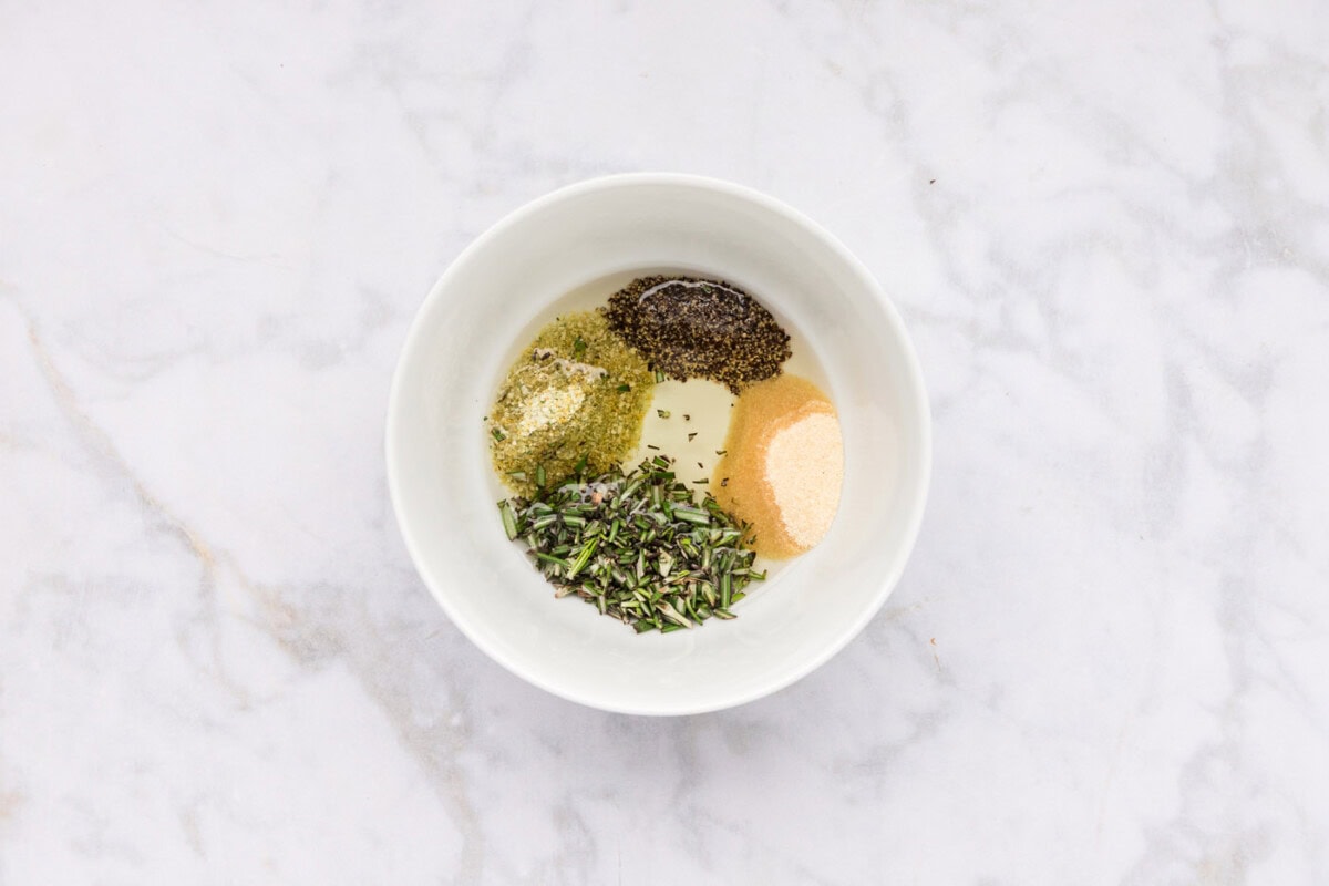 olive oil, pepper, garlic salt, onion powder, and rosemary leaves in a bowl