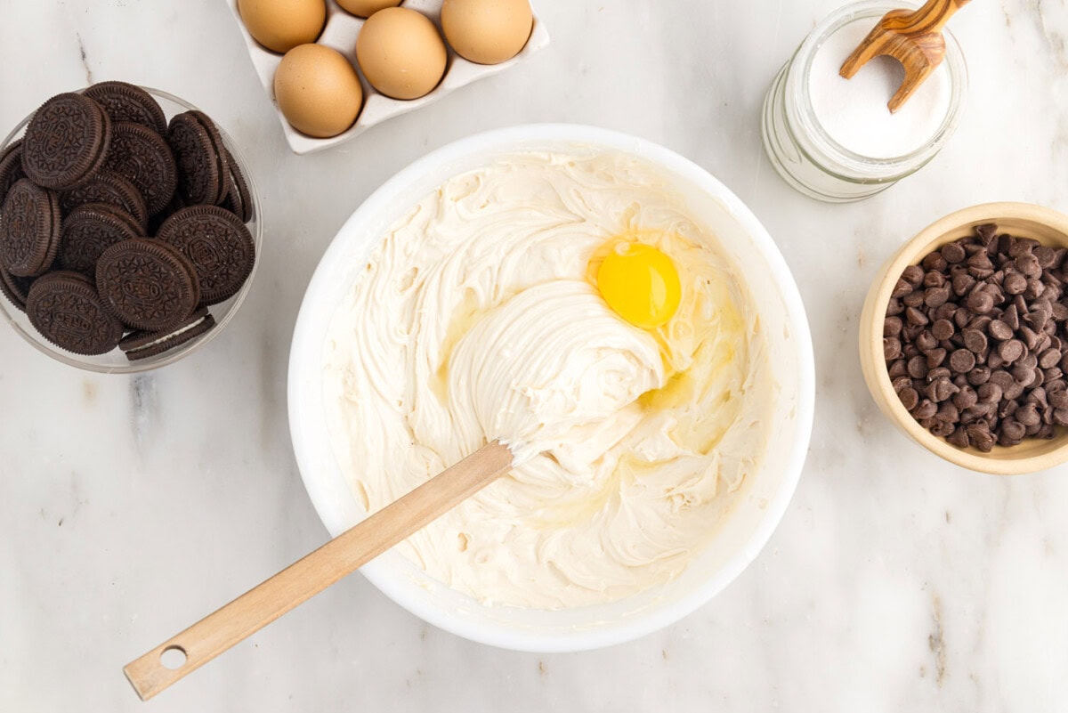 adding an egg to cheesecake batter