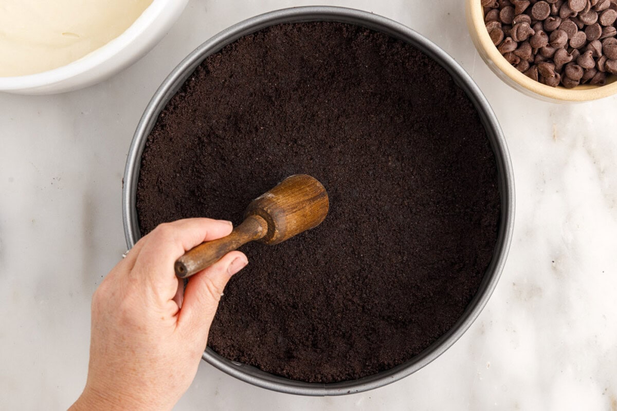flattening oreo crumbs into a springform pan
