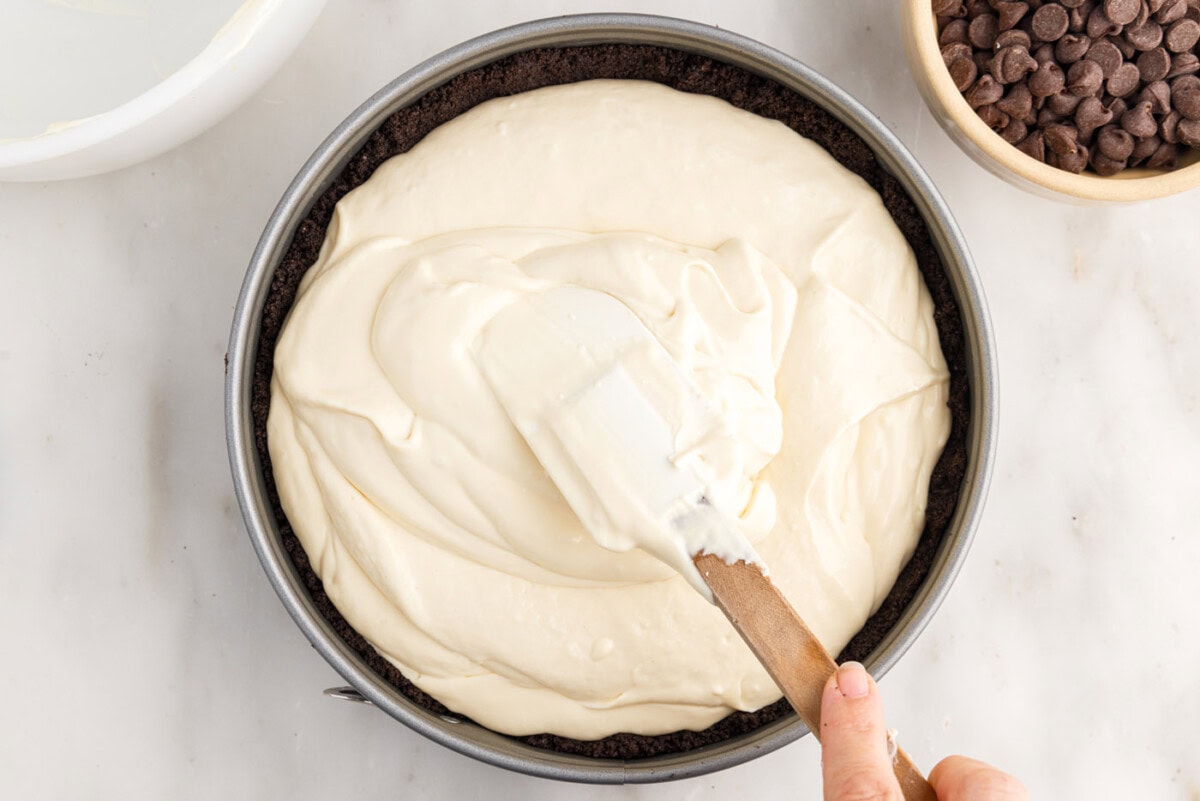 spreading cheesecake filling on top of Oreo crust