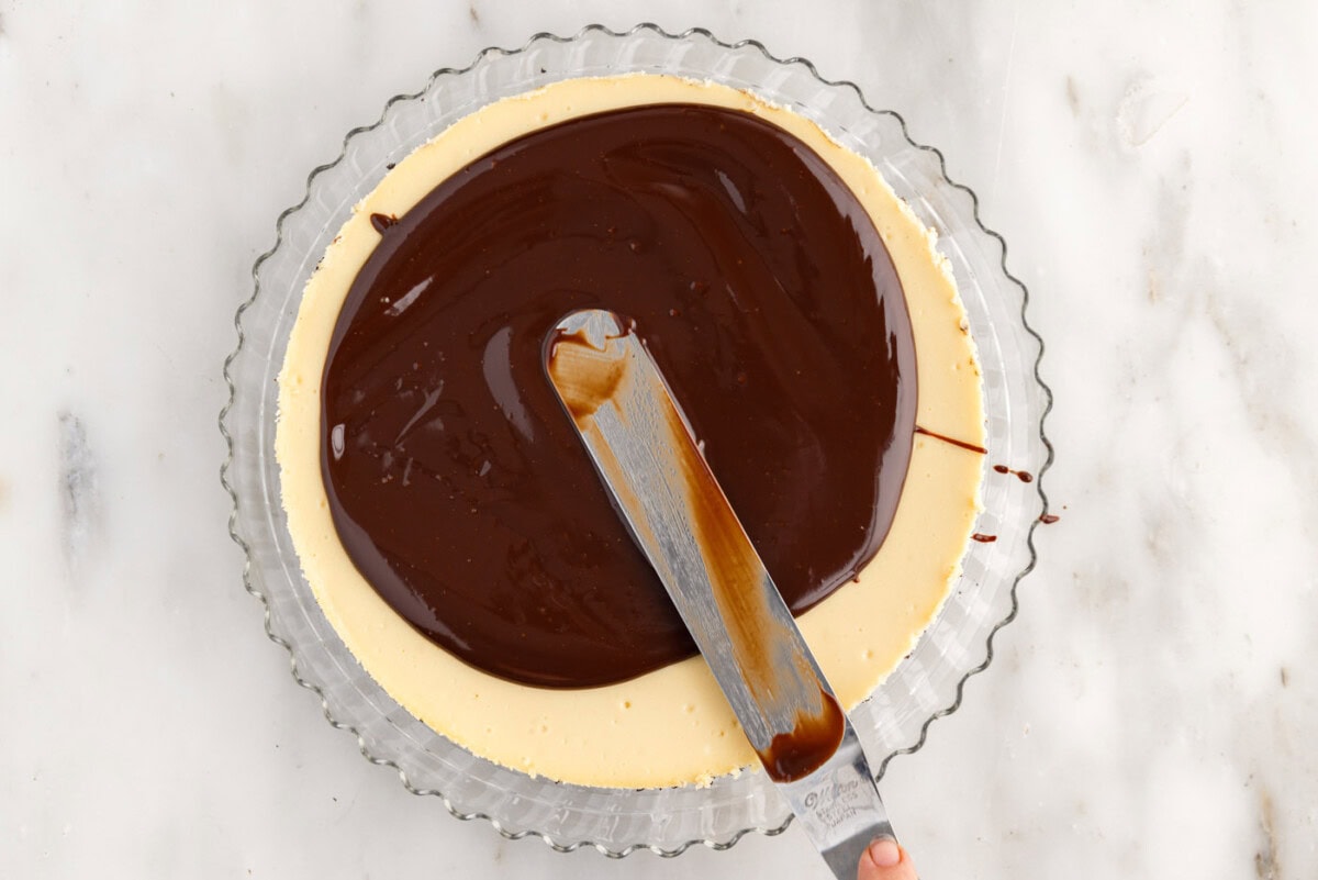 spreading chocolate ganache on top of cheesecake