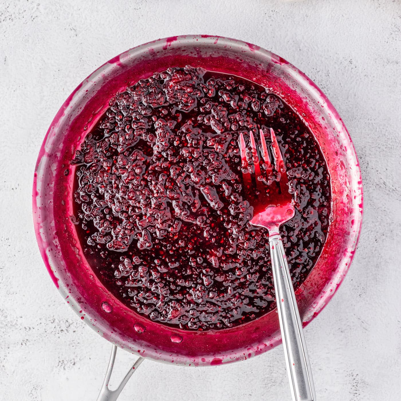 blackberry reduction with a fork in a saucepan