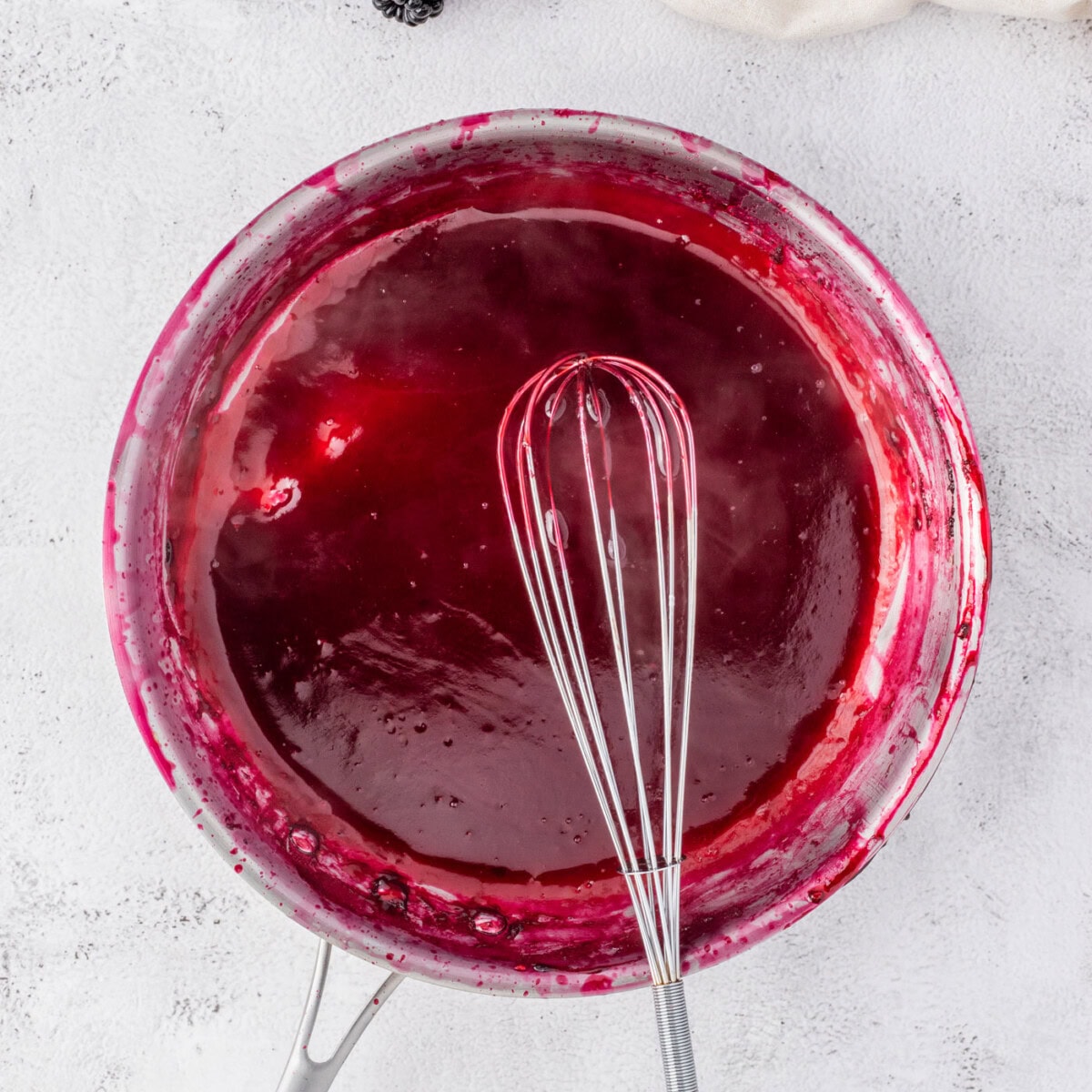 whisking blackberry reduction in a bowl