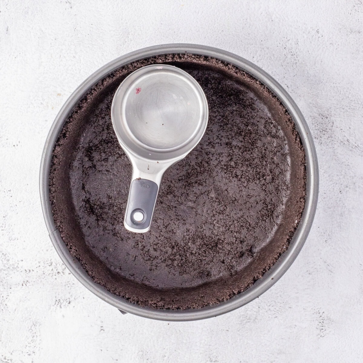 pressing Oreo cookie crumbs into a springform pan