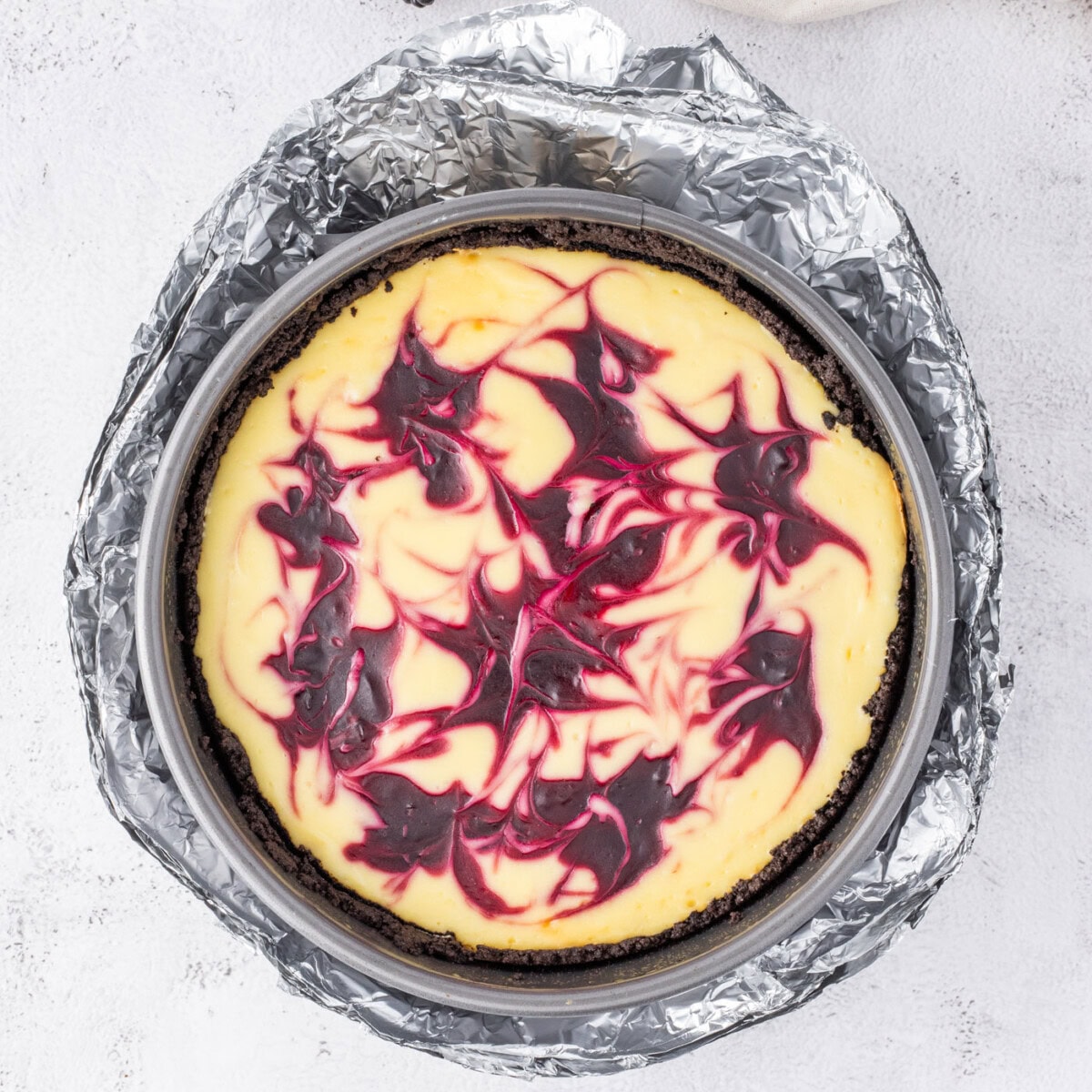 baked blackberry swirl cheesecake wrapped in aluminum foil
