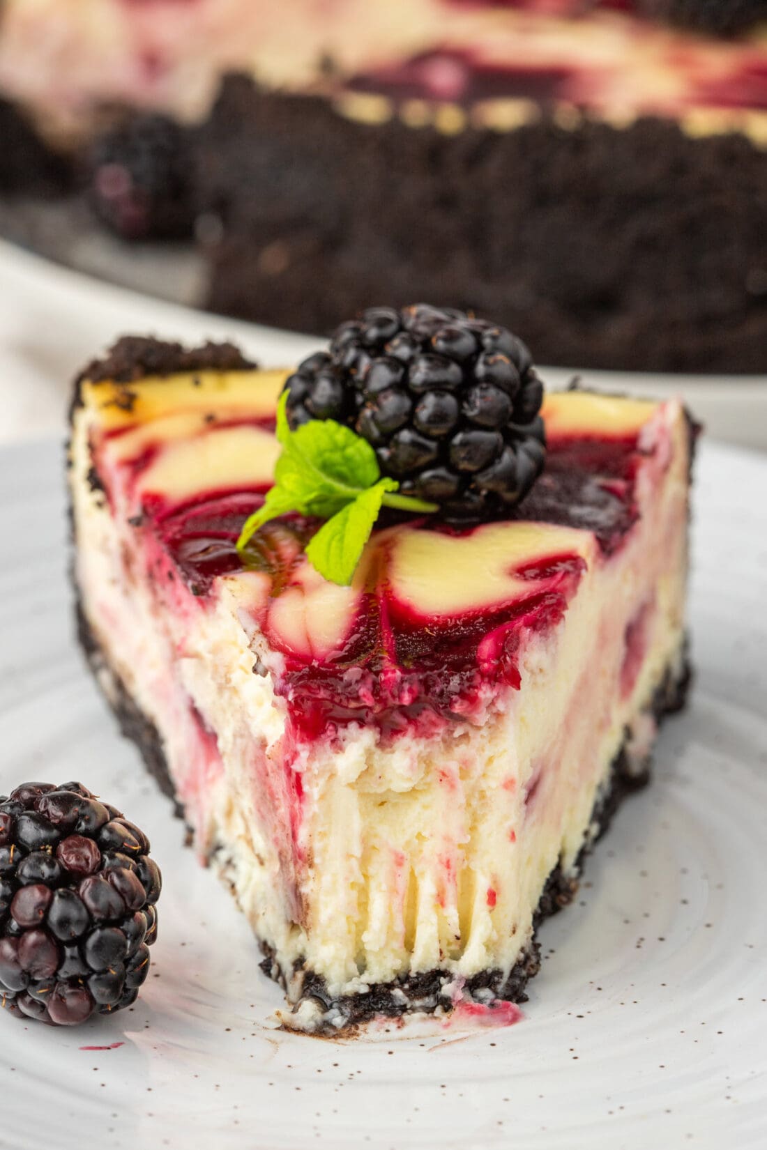 Slice of Blackberry Swirl Cheesecake on a plate with a bite taken out