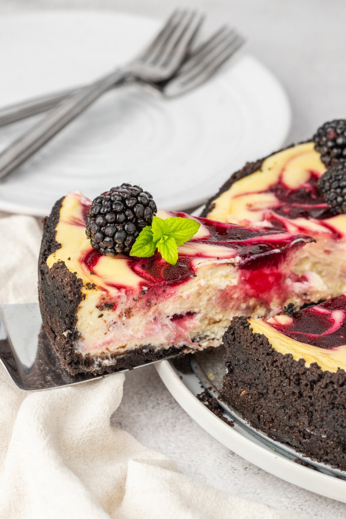 Slice of Blackberry Swirl Cheesecake being lifted away from the whole cheesecake