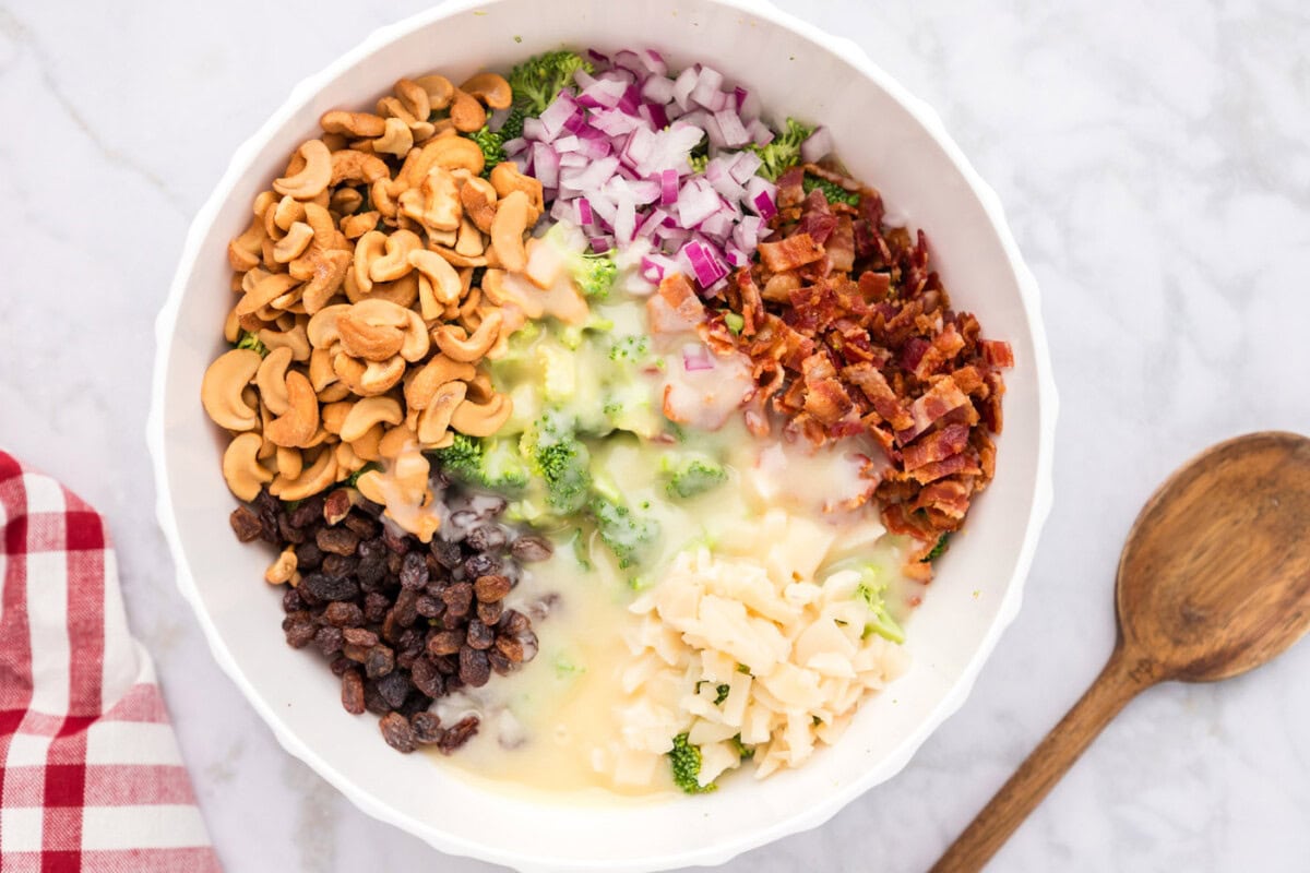 dressing poured over broccoli salad ingredients