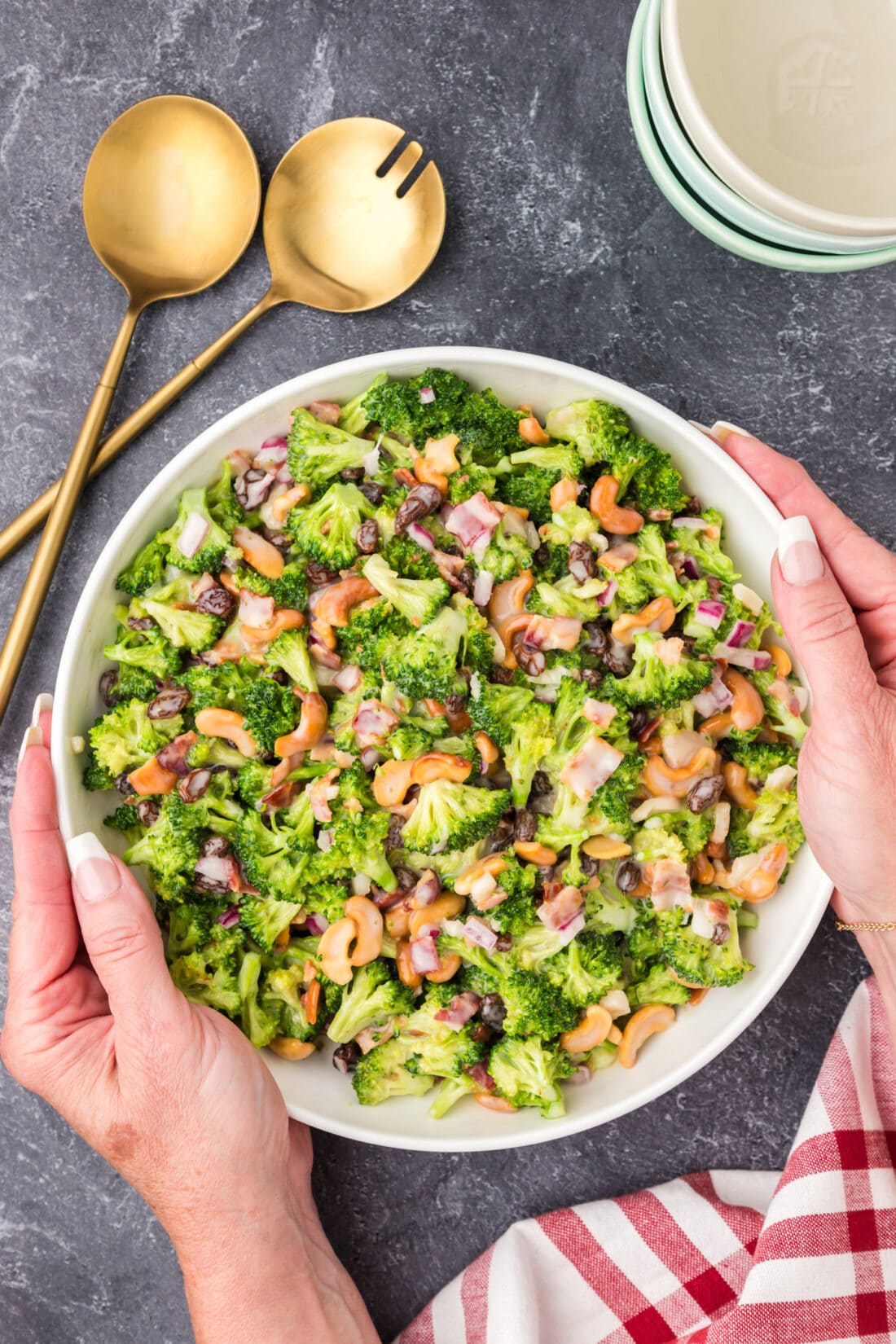 Hands holding a bowl of Broccoli Cashew Salad