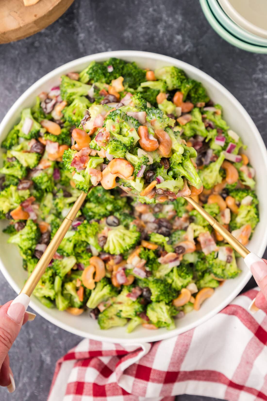 Two spoons holding up Broccoli Cashew Salad from a bowl