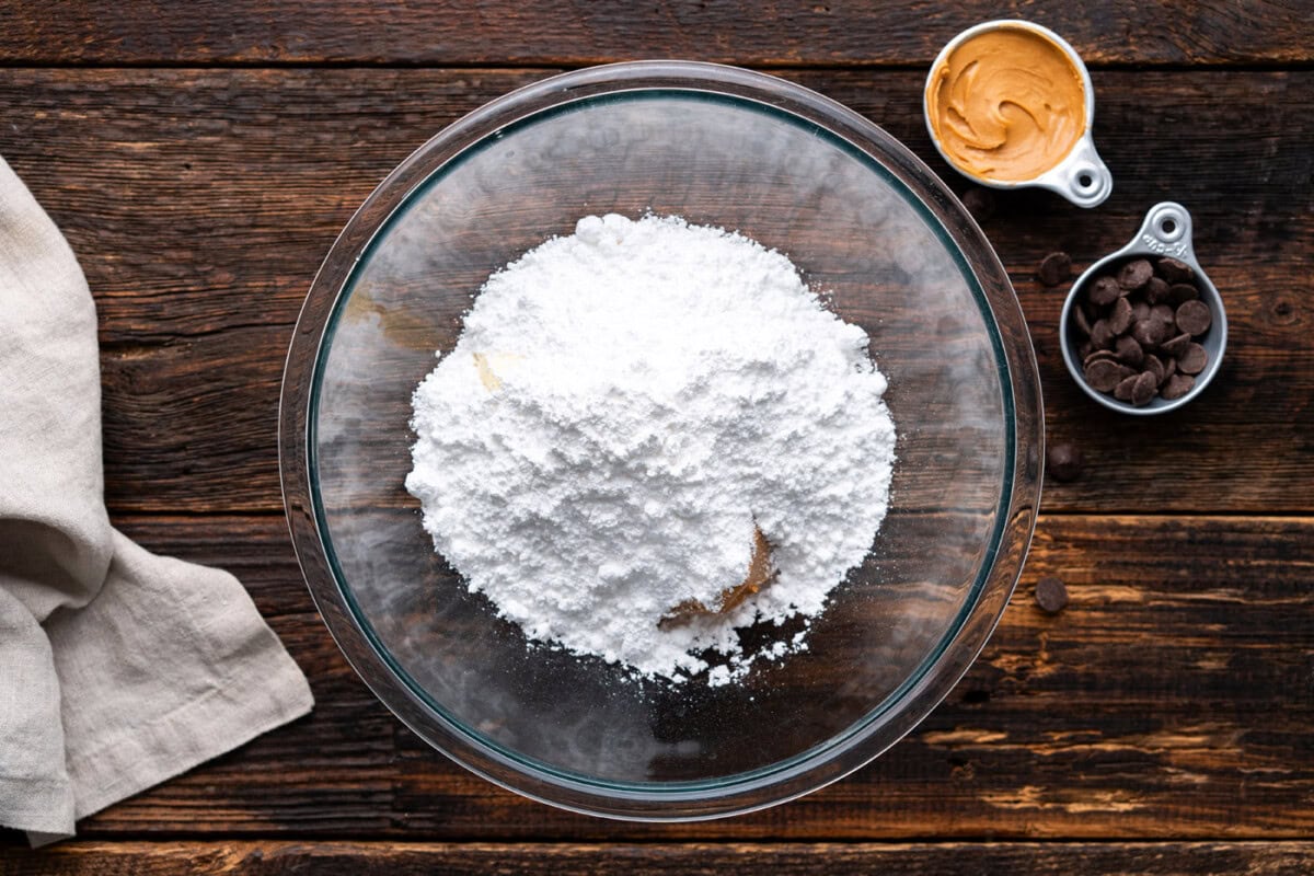 adding powdered sugar to peanut butter mixture in a bowl