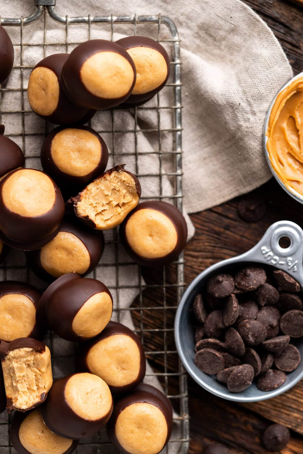 Close up photo of Buckeye Candy on a wire rack next to chocolate chips and peanut butter