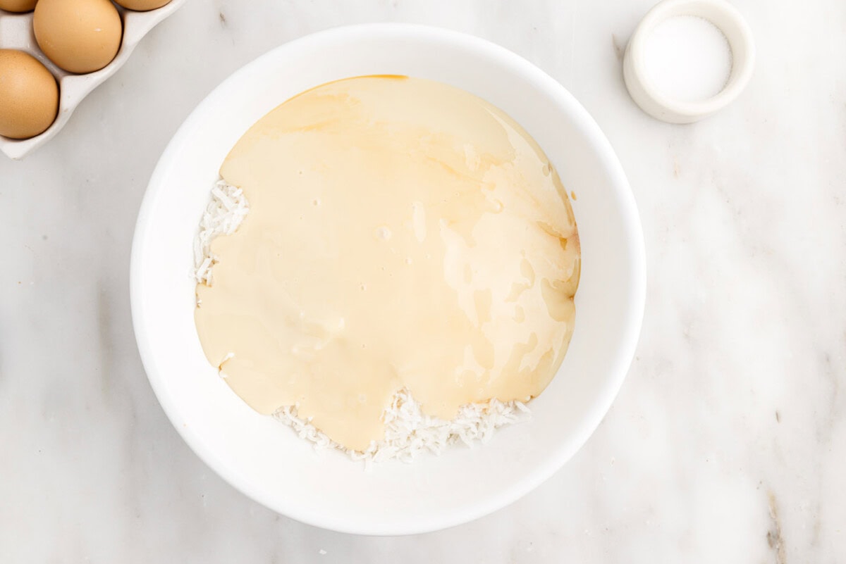 sweetened condensed milk with shredded coconut and vanilla in a bowl