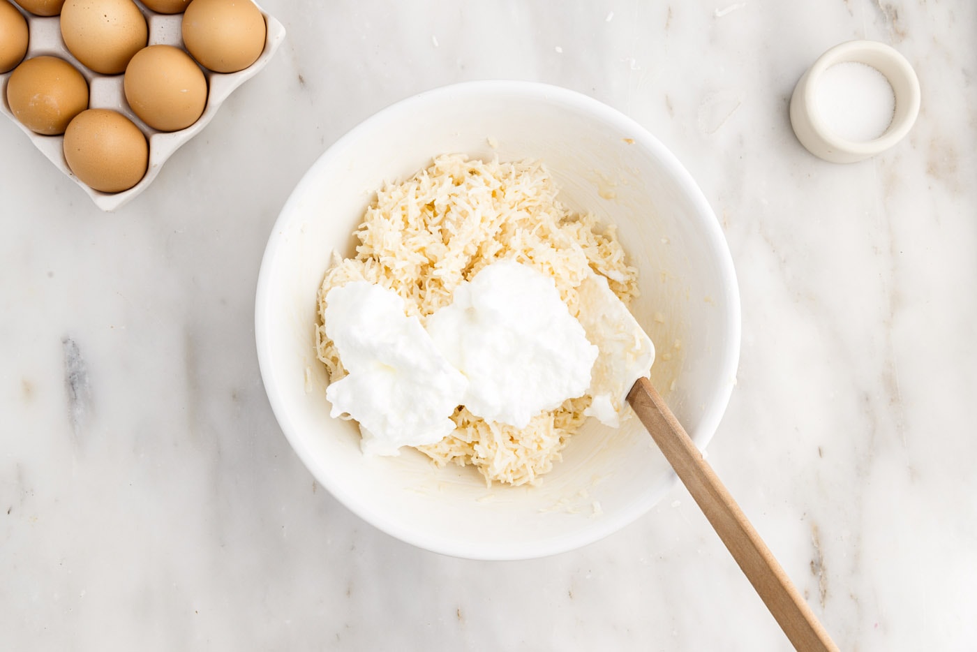 rubber spatula folding whipped egg whites into shredded coconut mixture