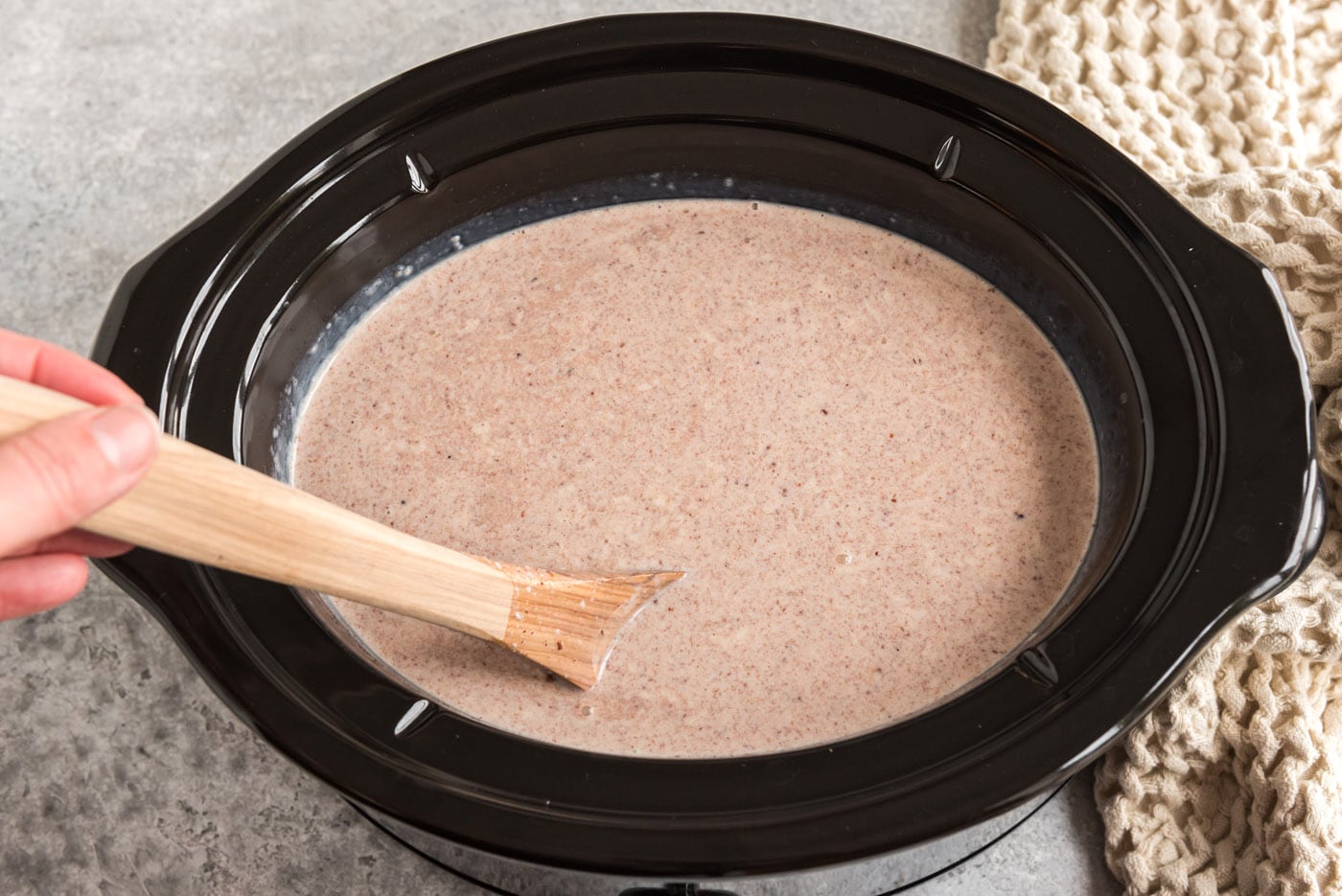 stirring crockpot hot chocolate with a wooden spoon