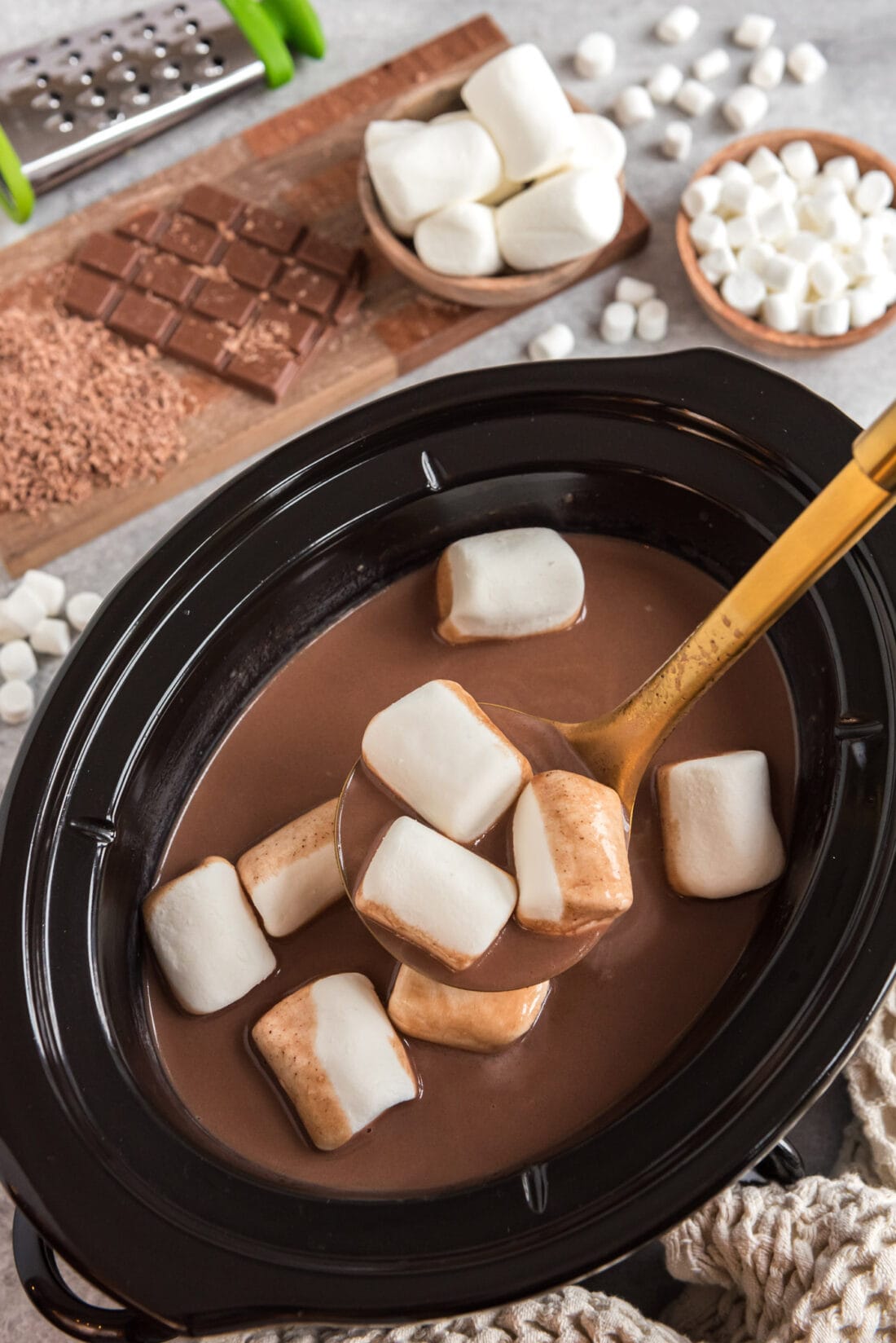 Spoonful of Crockpot Hot Chocolate with marshmallows being lifted out of the crockpot