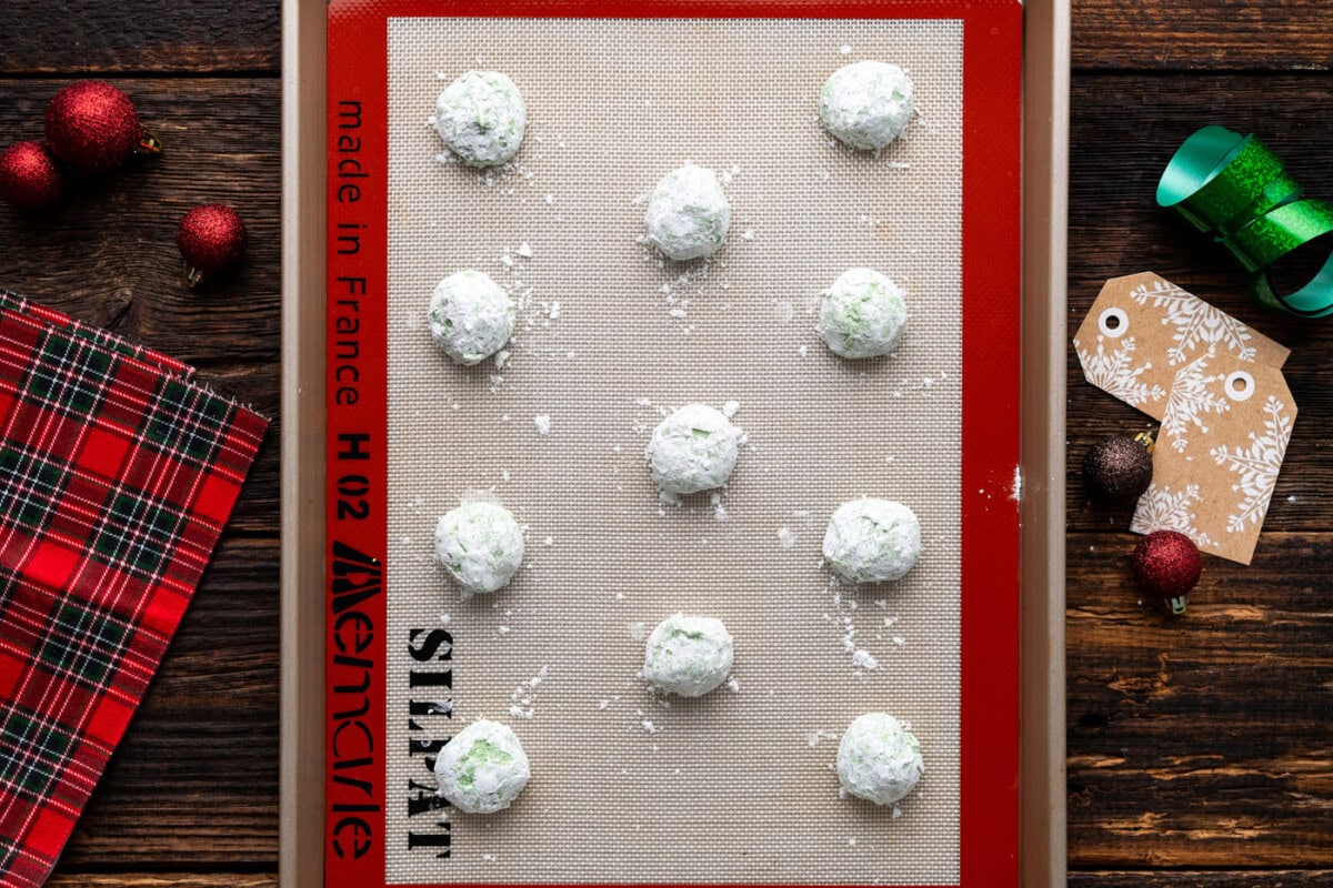powdered sugar coated grinch cookies on a baking sheet